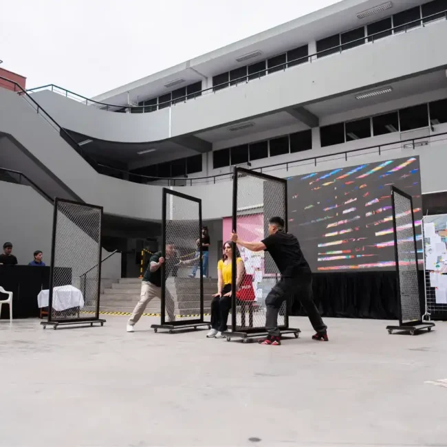 Performance artística en un patio universitario con estructuras de malla metálica