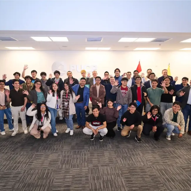 Grupo de estudiantes y docentes posando para una foto en una sala de la PUCP
